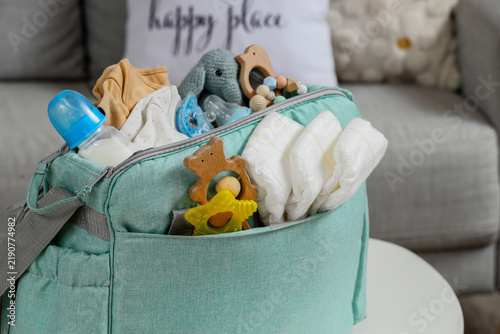 Baby bag with accessories on table in living room, closeup