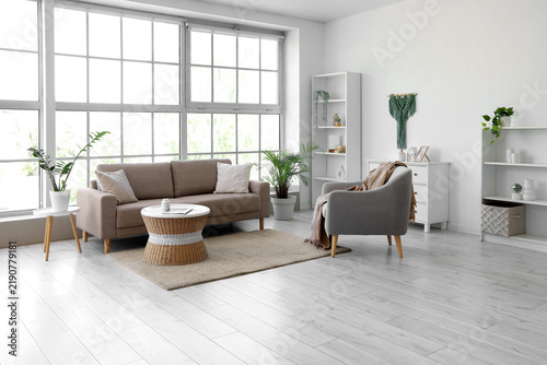 Interior of living room with soft couch, armchair and rattan table