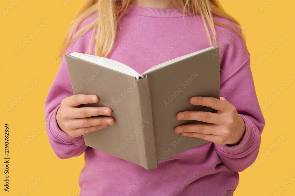 Obraz premium Little girl with book on yellow background