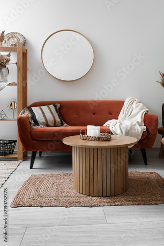 Interior of living room with brown sofa, mirror and coffee table