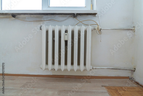 Fotografie Old apartment interior with outdated cast iron radiator, exposed wiring and mism