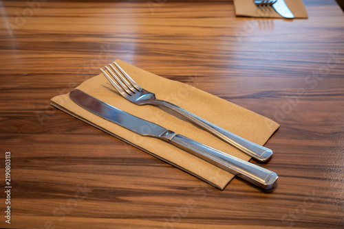 Table setting with cutlery on wooden surface at a dining establishment during lunch