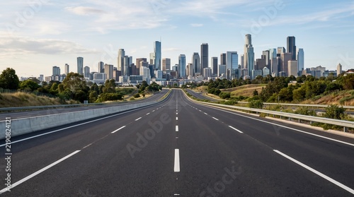 Deserted road stretching towards a contemporary city skyline during sunset