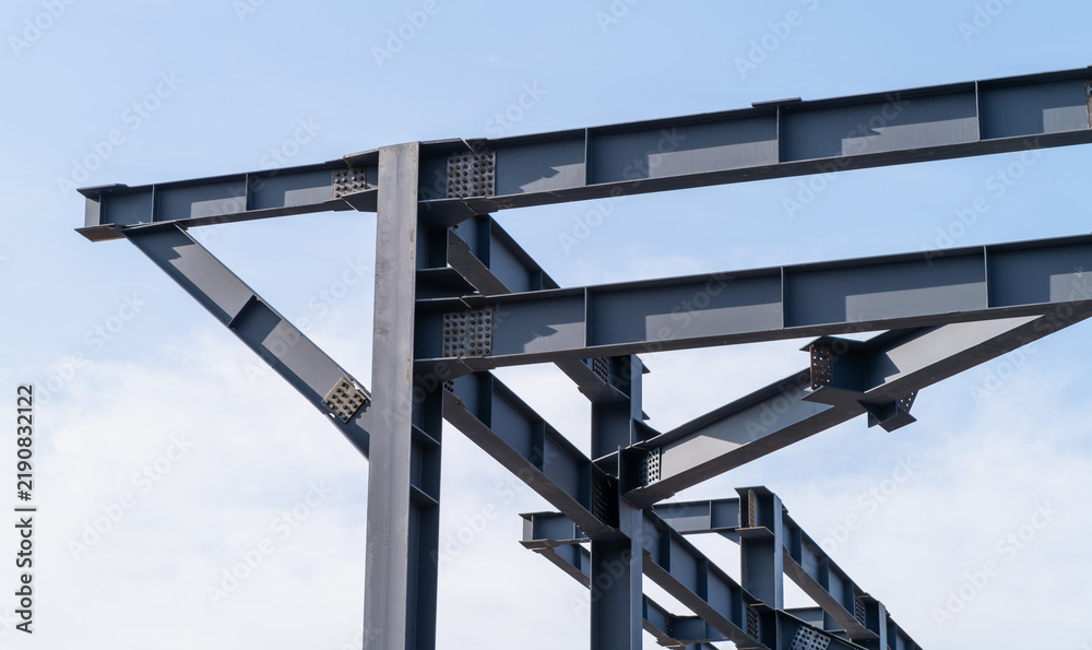 Obraz premium Close-up of a bolted steel frame joint with H-beams, columns and diagonal braces. Structural steel framework for an industrial building with beams, columns and support elements.