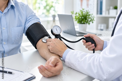 Professional doctor checking the blood pressure of a male patient in a clinic.