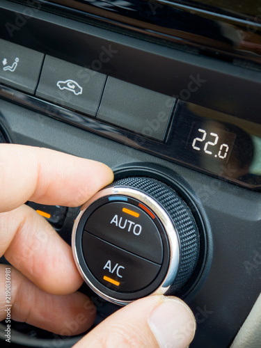 Hand Adjusting Temperature Knob on Modern Car Climate Control Panel