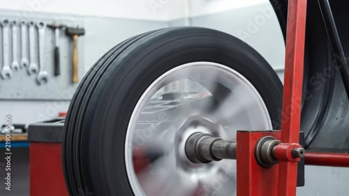 Mechanic balancing car tire on dynamic wheel balancer machine inside auto repair shop