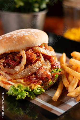 Gourmet burger with crispy bacon, caramelized onions, and golden fries