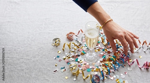 Hand reaching for champagne and confetti on a table celebrating a special occasion