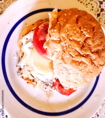 Фотография Large burger on a plate, lunchtime. Modern color photo.