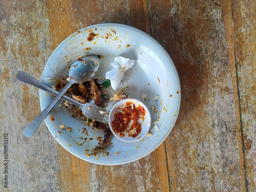 Dirty empty plate with leftover food and cutlery on a wooden table