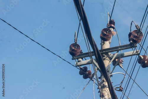 Electric utility pole with power lines and glass insulators against blue sky