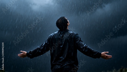 Man with Arms Open Embracing Heavy Rain in a Serene and Reflective Moment
