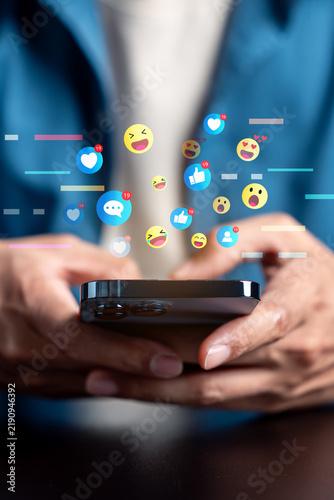 Social media network communication and online engagement reaction. Man hand holding smartphone using emoji emoticon heart like and message.