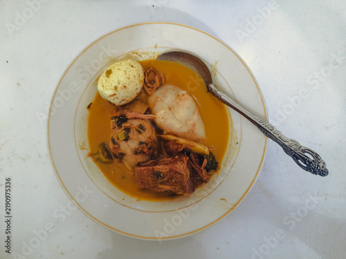 Katupek Pitalah is a traditional Minangkabau dish from Padang Panjang, West Sumatra, featuring rice cake, aged jackfruit curry, boiled egg, noodles and aromatic herbs.
