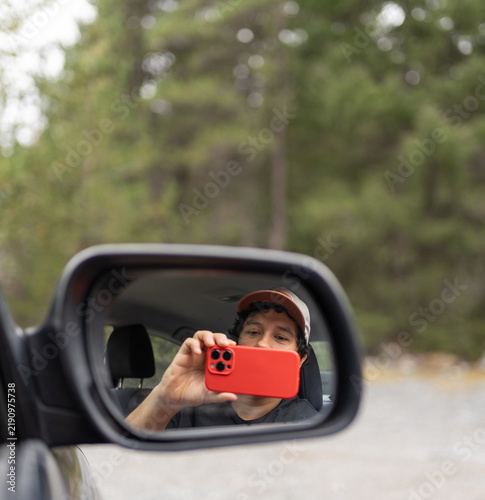 A man taking a photo from a car window