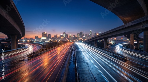Dynamic multilane highway interchange at twilight with dramatic long exposure light trails and a modern city skyline, illustrating urban transportation, mobility, infrastructure, traffic flow, and con