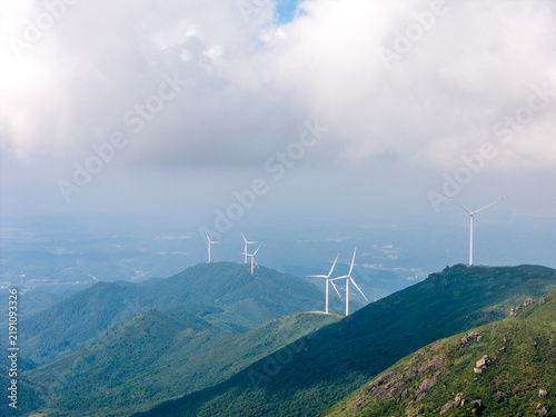 Photography White wind turbines standing on rolling green mountains under cloudy sky