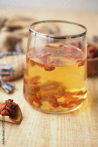 Fotografie Tea with goji berries in a glass on a wooden table