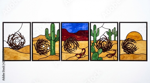 Stained glass five panel sequence showing a tumbleweed creature rolling through a desert landscape