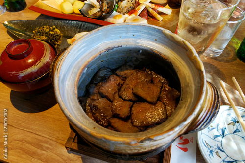 Obraz na płótnie apanese grilled Bungo beef claypot rice served in traditional earthenware pot with side dishes and chopsticks on a wooden table