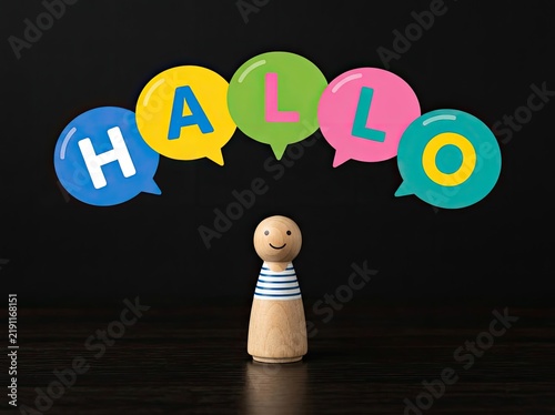 Wooden figure under colorful hallo speech bubbles ideal for language learning media symbolizing friendly greetings and welcoming connection