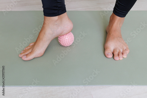 Foto Bare foot presses a spiky massage ball under the arch during preventive foot exercise for plantar fascia release, arch mobility, muscle activation and sole stimulation