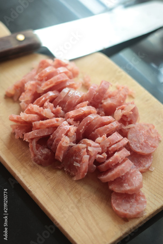 Sliced fermented pork sausage (naem) arranged on a wooden cutting board.