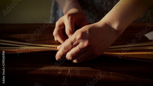 Close up of hands handling and organizing analog motion picture film strips on a dark wooden surface, highlighting vintage cinematography, tactile media editing, and archival processes.
