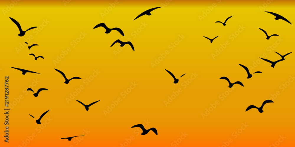Fototapeta premium The silhouette of a flock of black birds in flight against a sky with yellow and orange color gradients, resembling a sunset scene.