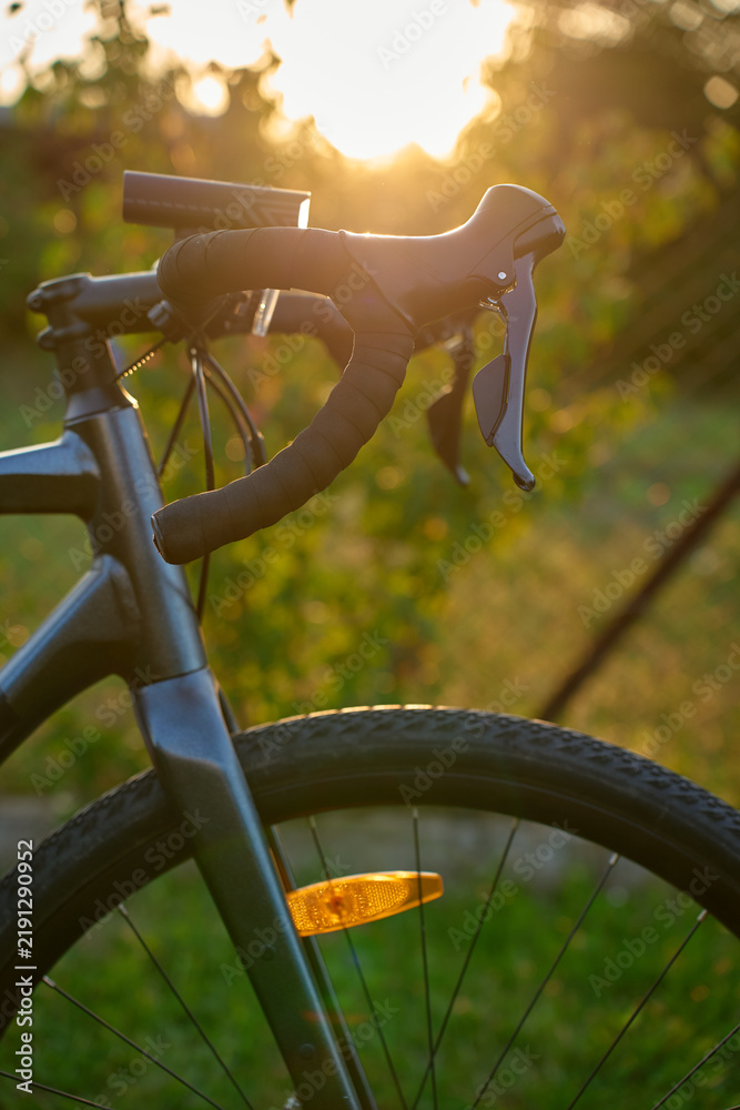 Obraz premium Close-up of a gravel bike with front wheel, drop handlebars at sunset