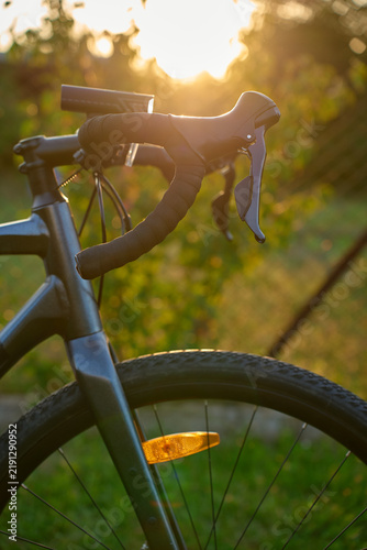 Close-up of a gravel bike with front wheel, drop handlebars at sunset