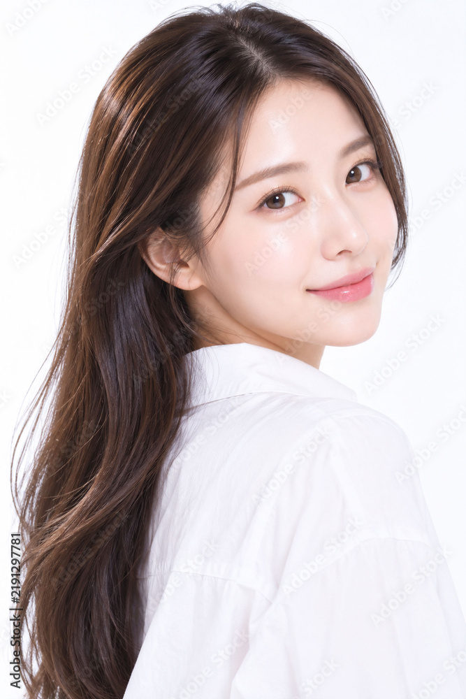 Fototapeta premium 白背景で振り向きながら自然に微笑む透明感のある日本人女性の美容ポートレート