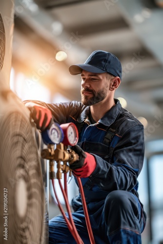 A professional technician installing refrigerant into a heat pump system, ensuring proper HVAC maintenance and efficient climate control in a residential or commercial setting.