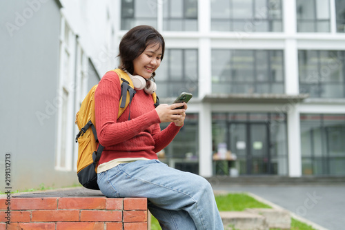 Asian college student smiling checking phone on campus