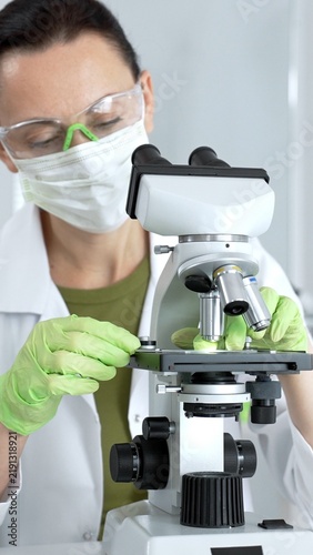 Konstfotografi Female scientist in laboratory coat and safety goggles closely examining samples