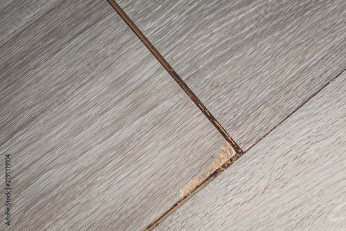 Bild auf Leinwand Damaged laminate flooring with chipped corner, exposed core, dark gaps between b
