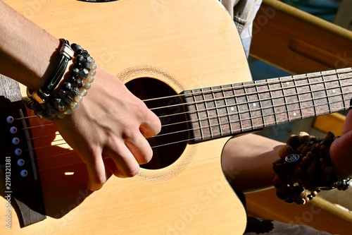 Foto Close-up of hand strumming acoustic guitar body on sunny balcony
