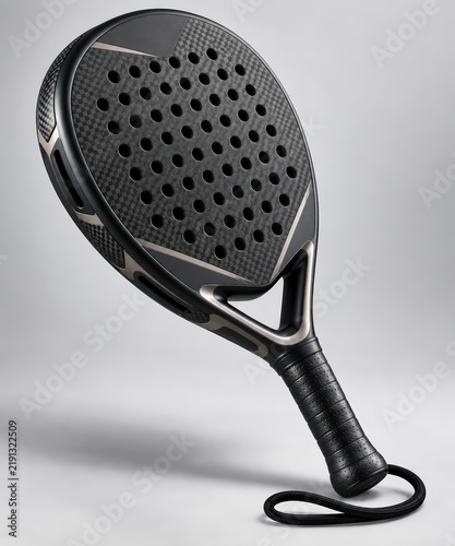 Elegant black padel racket with a textured carbon fiber surface and array of perforations, photographed from an engaging angle on a light gray studio background.