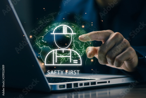 Business professional using a laptop with a virtual global safety interface, representing workplace safety, risk management, employee protection, compliance, and secure digital operations.