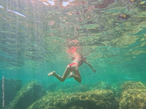Фотография Young woman in red bikini swimming and snorkeling in shallow turquoise Mediterra