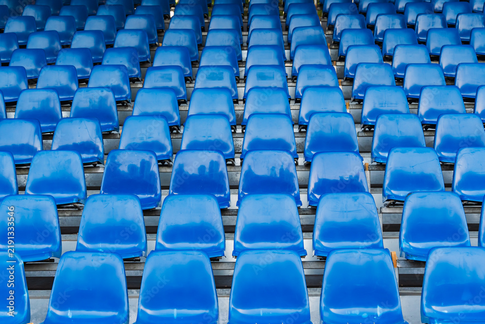Fototapeta premium Rows of empty blue plastic seats in stadium, repeated seating pattern in sports arena grandstand, outdoor tribune background, nobody, daytime