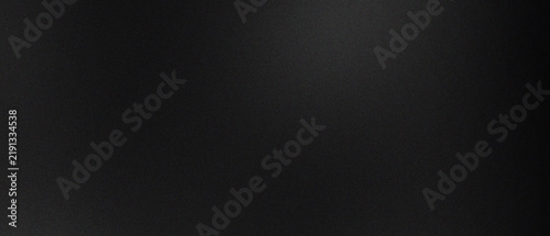 A textured black surface with subtle grain and soft ambient lighting gradient