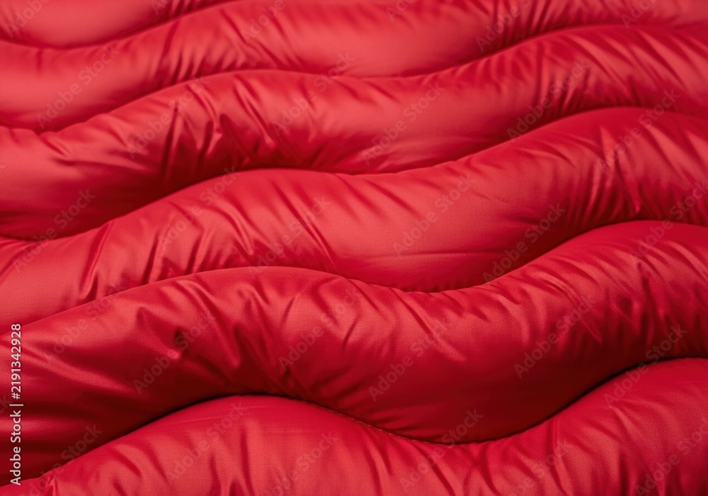 Obraz premium Abstract background of bright red wavy quilted fabric pattern.