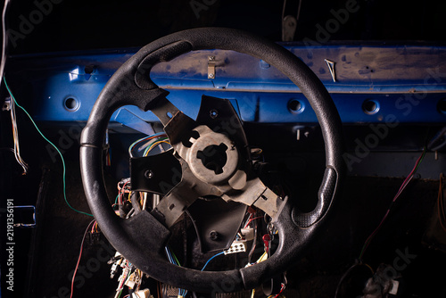 Disassembled steering wheel without horn horn-button cap inside gutted car dashboard cabin body