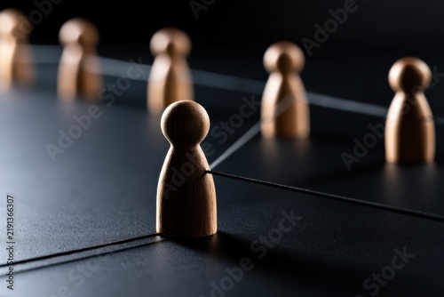Wooden figures connected by strings on a dark surface symbolize networking, team collaboration, and social connections in a conceptual arrangement