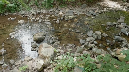 Small mountain stream with crystal clear mountain water flowing over rocks and stones