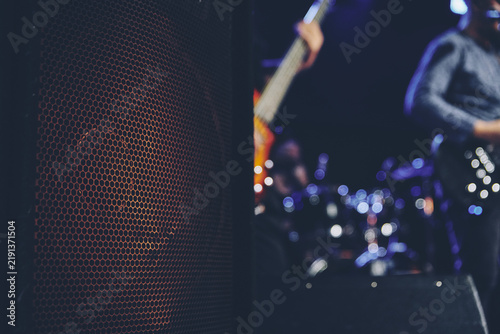 Concert speaker cabinet beside guitarist on dark stage with blue light