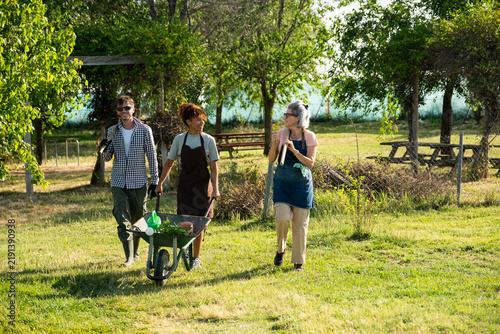 Group of multi generational gardeners walking and carrying tools in an urban farm