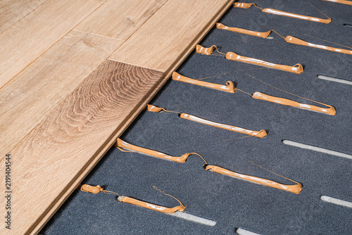 Laying parquet wooden floor using sound insulation underlayment and adhesive system